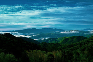Lush green mountain ranges with sea of clouds under blue sky