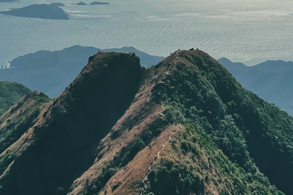 Hikers on sharp mountain peak above sea
